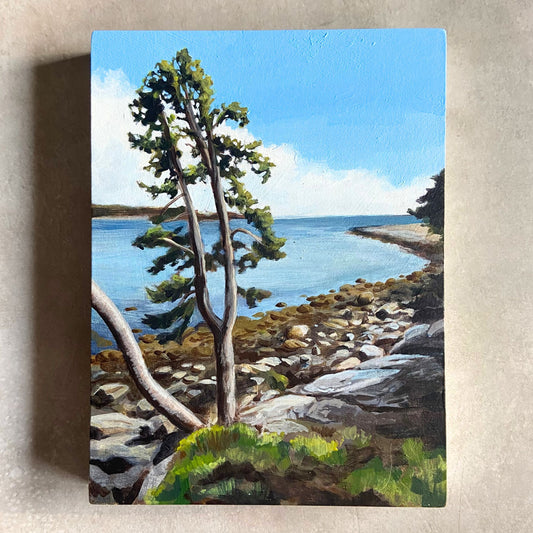 An acrylic coastal landscape painting on wood panel sitting on a textured background. the painting, portrait-oriented, depicts a bay on the ocean on a blue-skied day. The beach is rocky and the focal point is a tree growing at the edge of the land.
