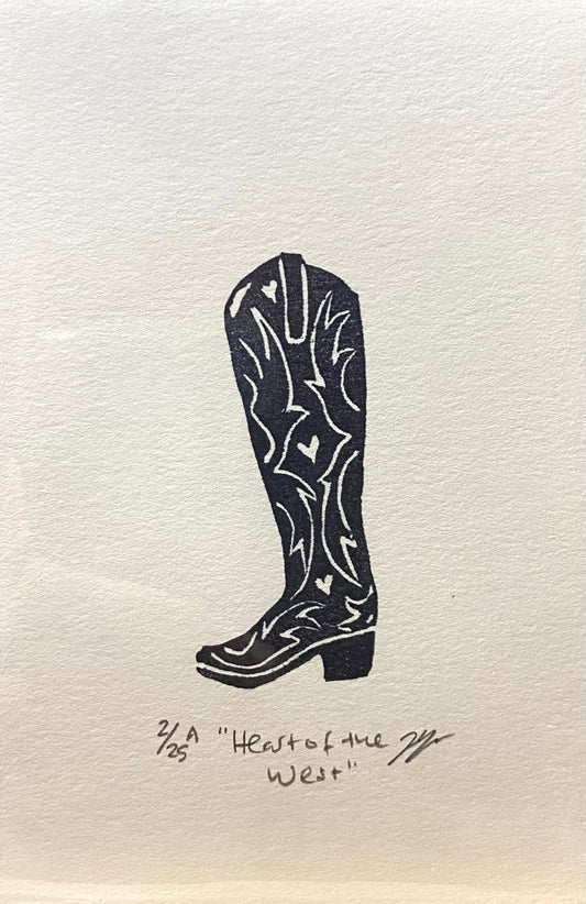 A black and white relief print of a cowgirl boot, made by hand using a carved eraser. The print is numbered, signed, and titled "Heart of the West".