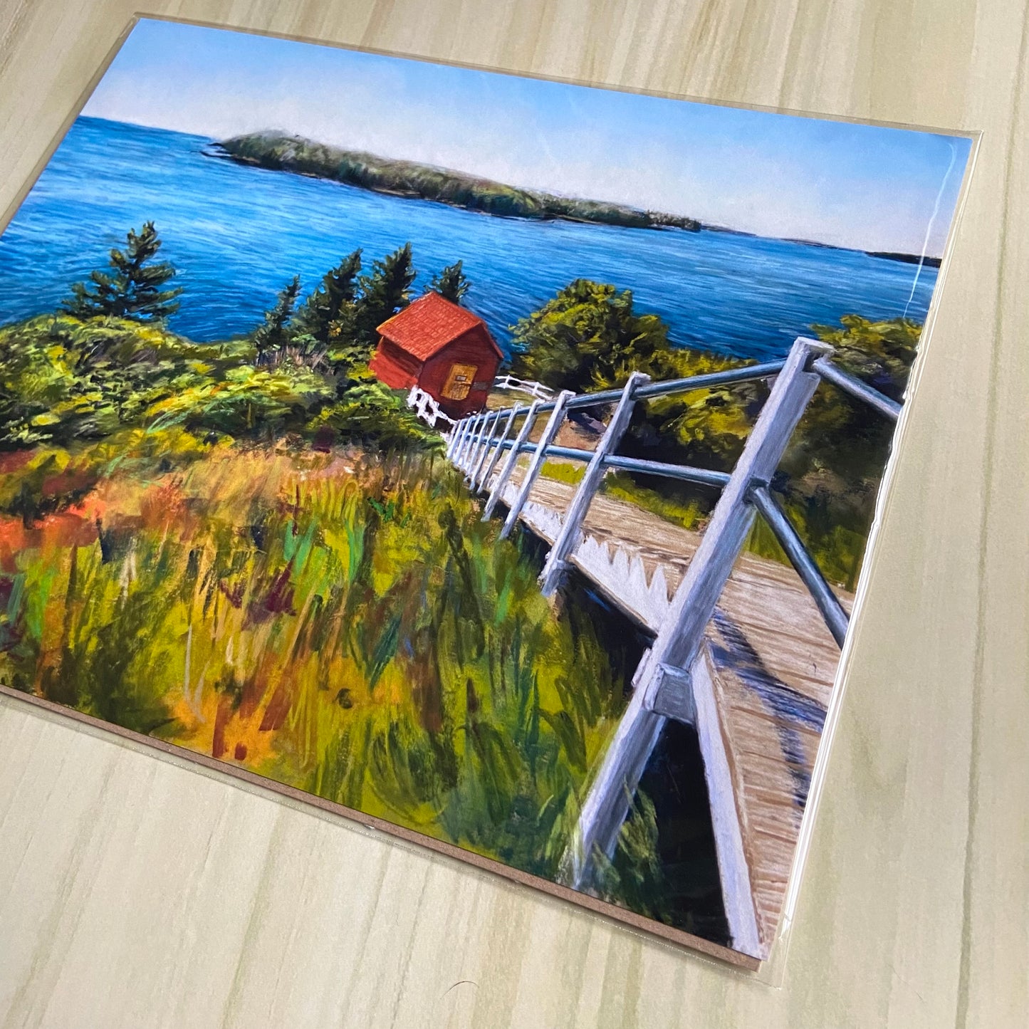 A detail view of the art print. The artwork is made with colorful pastels with expressive marks and visible texture. The red building at the end of the staircase draws your eye amidst the blue and green seascape/landscape.