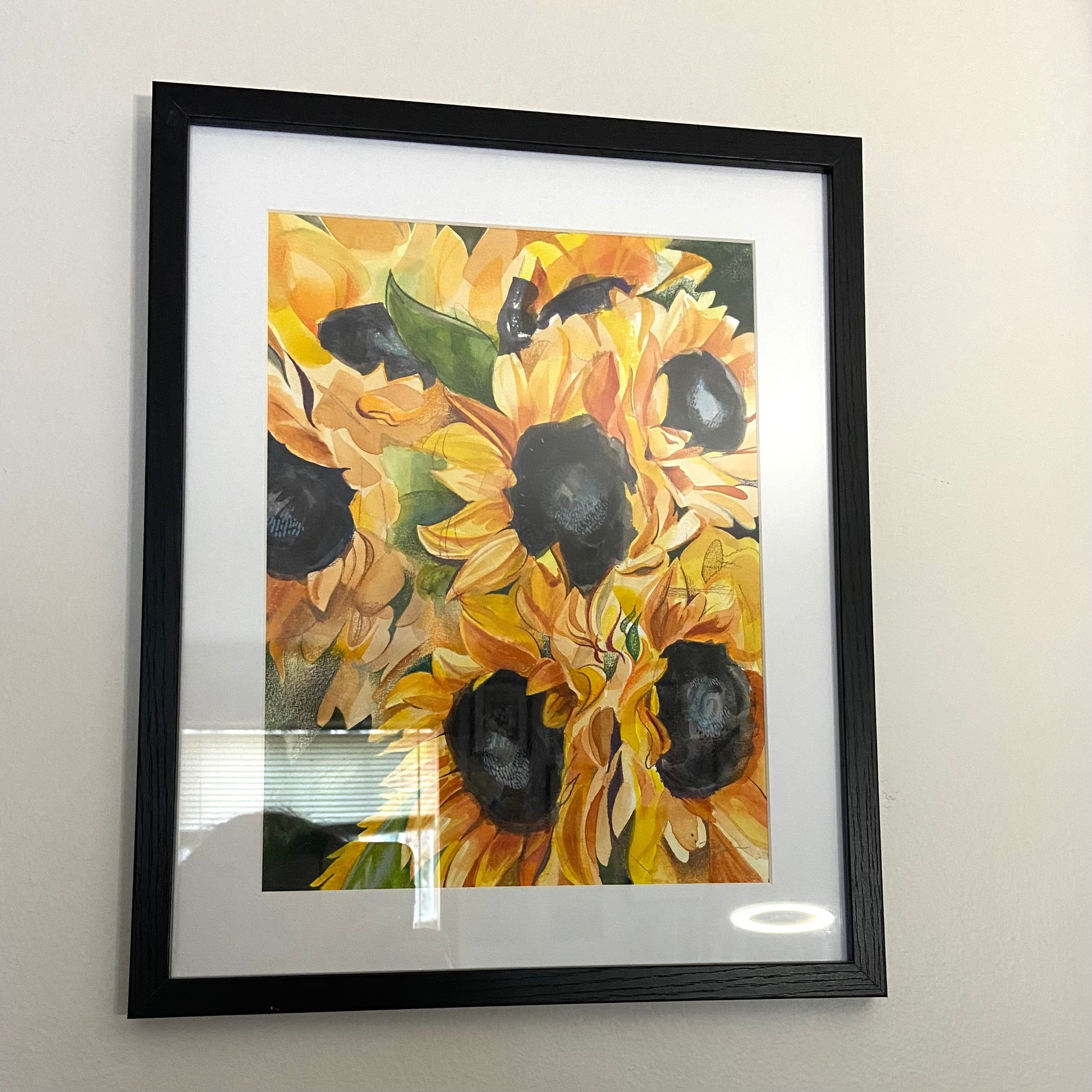 A vibrant mixed media (mostly watercolor) painting of several sunflowers. The artwork is in a black frame with a white mat.