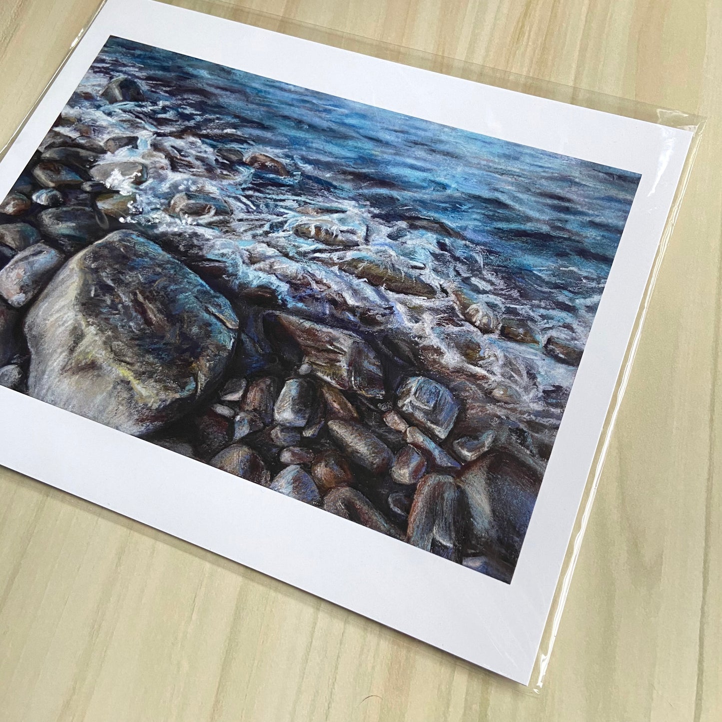 A detail look at the blue art print. The sea's waves gently lapping on the shore's rocks are relaxing and realistically detailed. The focal point is the largest rock, at the bottom and slightly left, and it shows highly detailed texture.