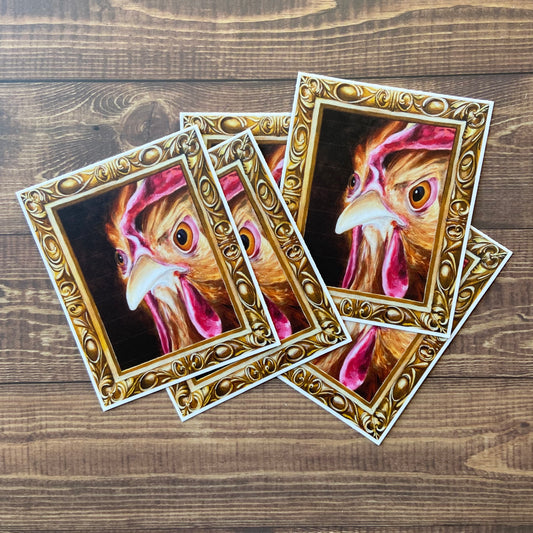 A small pile of stickers of my painting, "Regal Chicken" or "Hennifer", depicting a hen's angry face inside an ornate gold frame (also painted.)