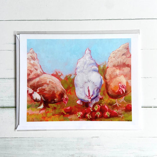 A white greeting card printed with an image of my painting, Strawberry Hens. One white hen flanked by two buff hens peck at a pile of ripe strawberries in this warm-toned acrylic painting.