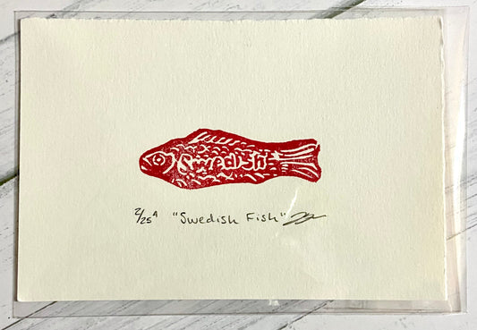 A red relief print of a Swedish Fish candy. The print is made by hand from an eraser and is numbered, titled, and signed.