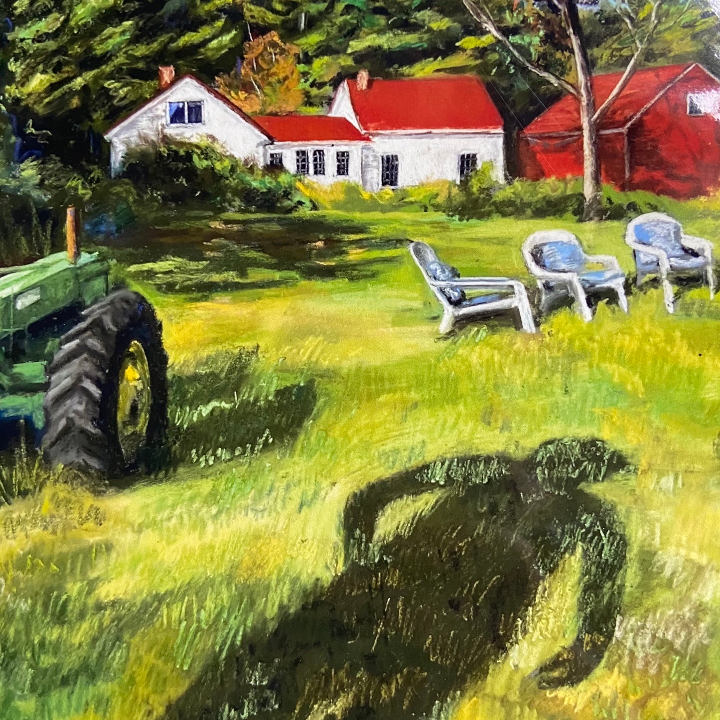 A close-up of the art print. The grass in front of the farmhouse is bright yellow-green. In frame is part of the John Deere tractor, three lawn chairs, and the white home with red barn. Part of the person's shadow is in view too.