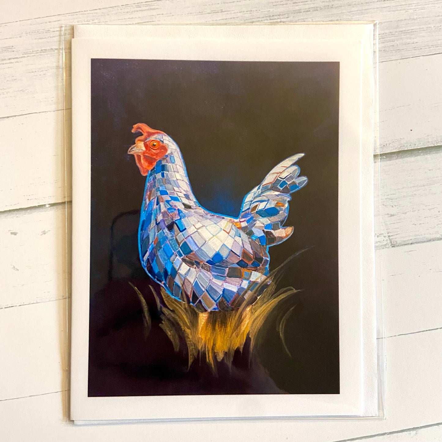 A folded white greeting card with an image of a painted mirrorball (disco ball) chicken on a dark background. 