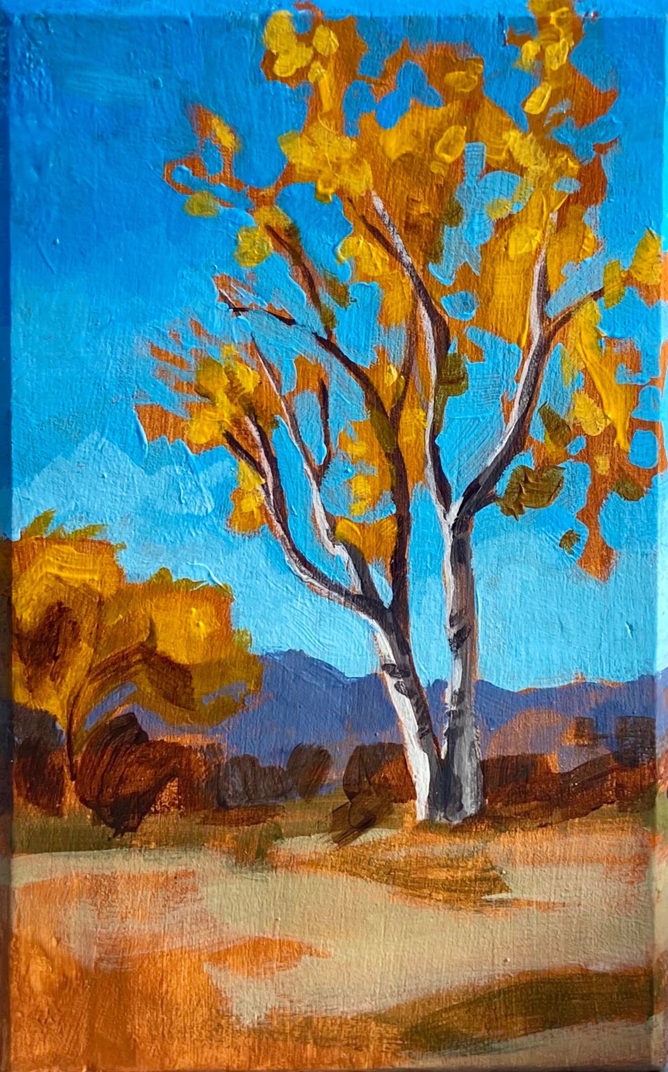 A painting of a yellow-foliated birch tree in a field before mountains, all under a bright blue sky. The image is cropped to the edges of the artwork. 