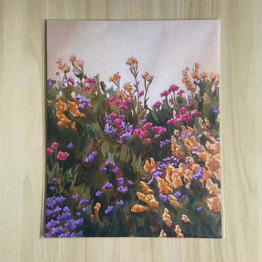 An 8x10 art print on paper, depicting a painting of gold, pink and purple flowers in a lush green field before a light golden sky.