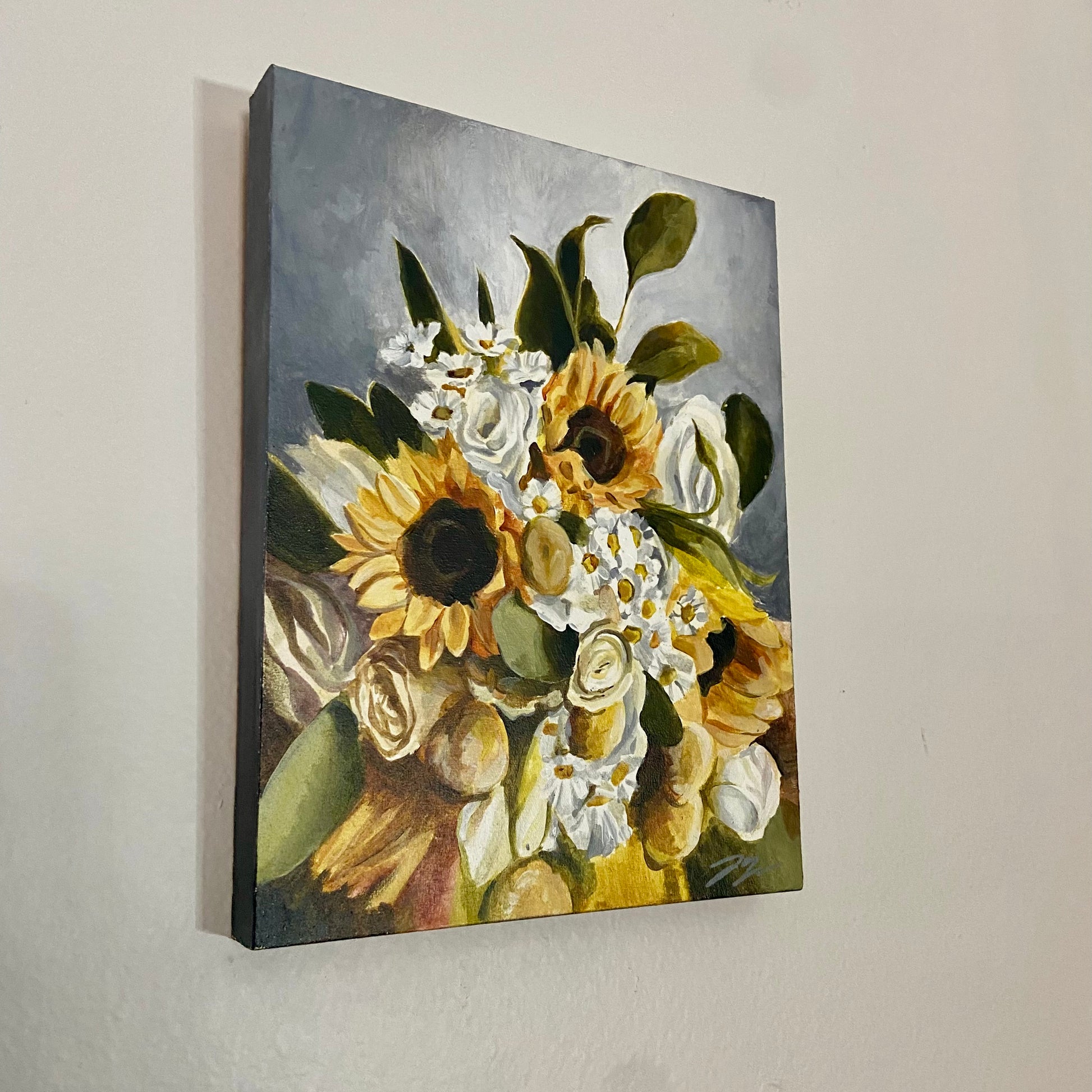 A painting of a bouquet of sunflowers hanging on a light gray wall. The background of the painting is also gray, making the yellow and green colors of the plants pop. 