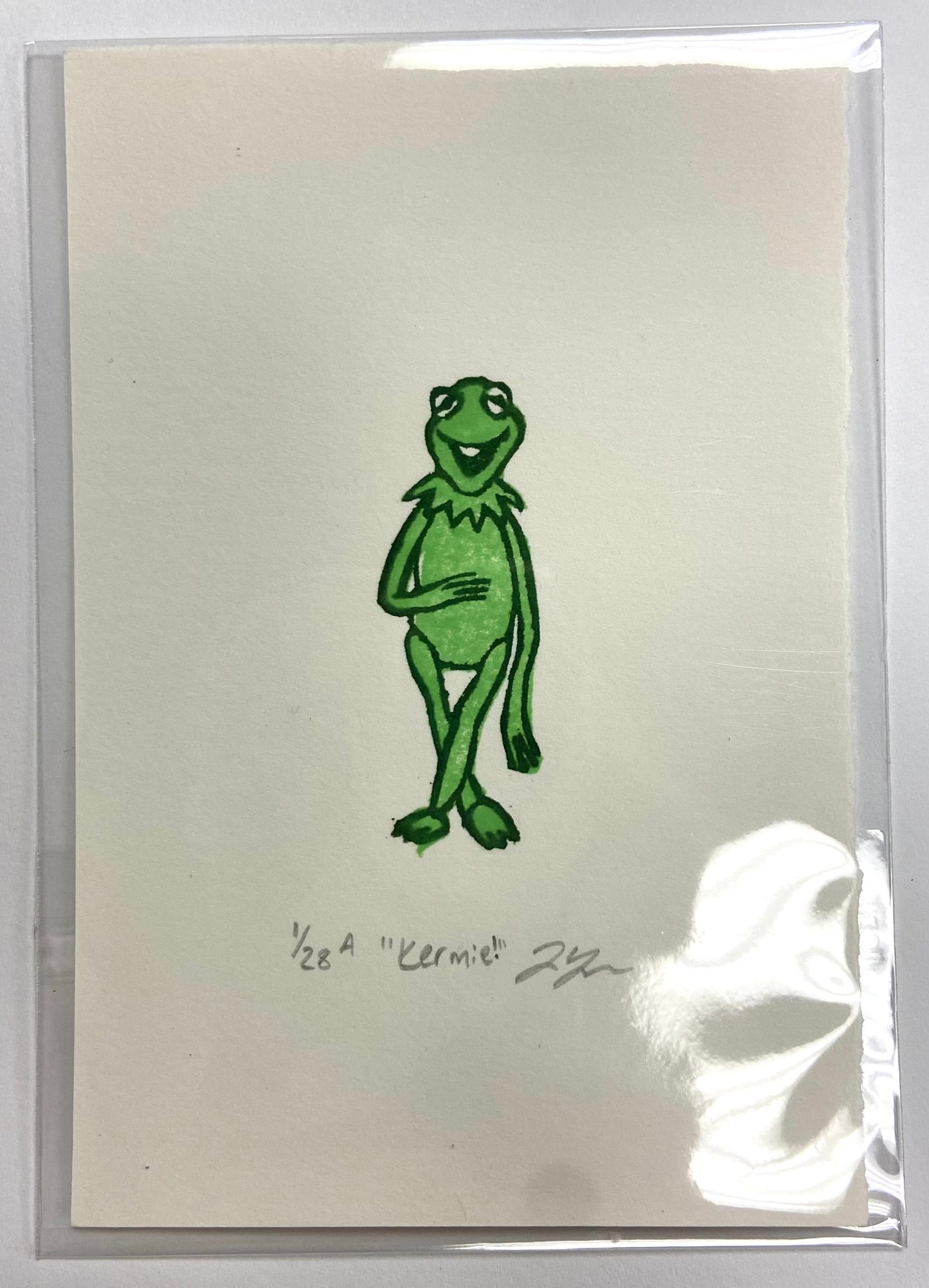 A green relief print of Kermit the Frog from the Muppet Show. The print is made by hand using carved erasers and is numbered, titled "Kermie!" and signed. 