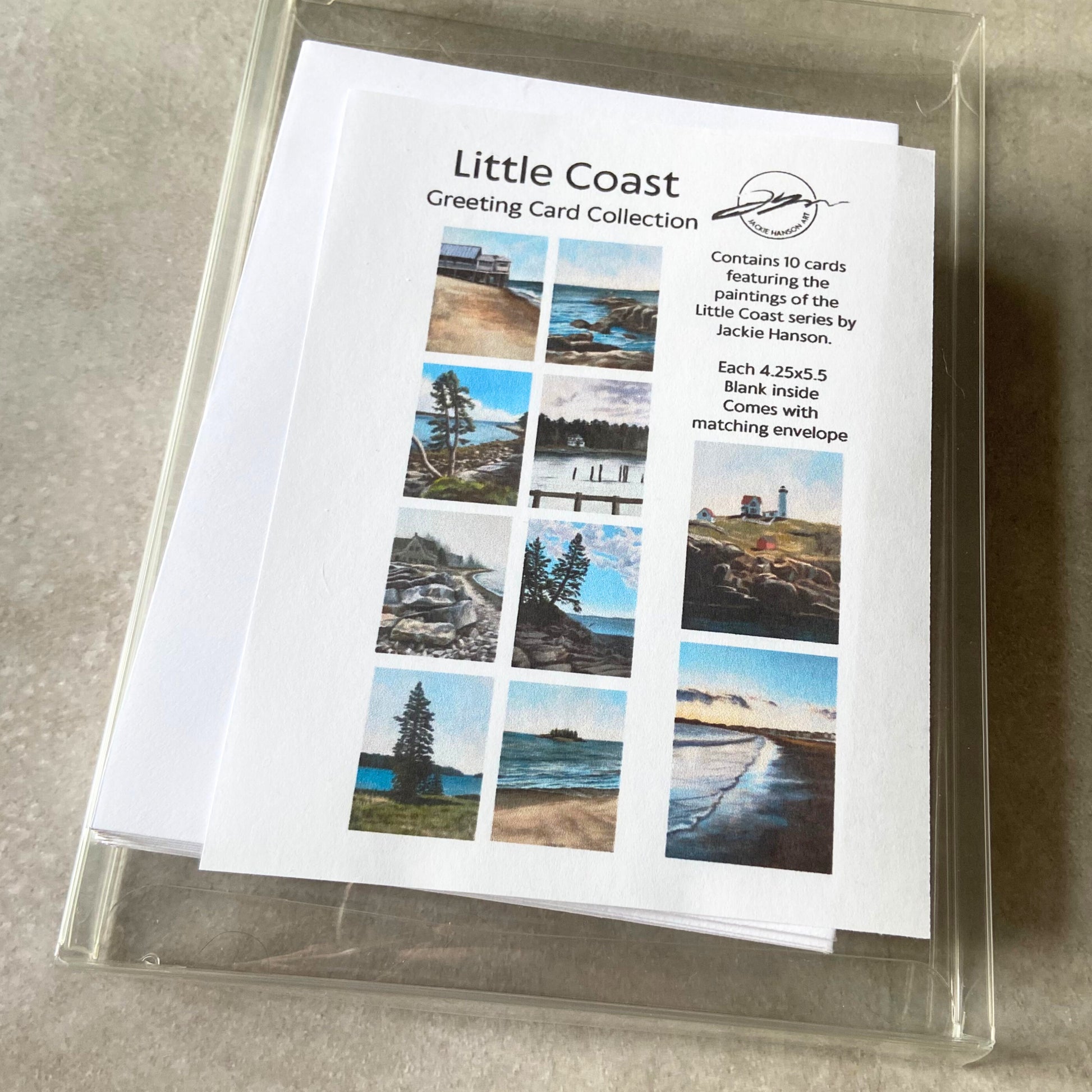 A clear box full of white envelopes and cards. There is a sheet inserted in the box with thumbnail images of ten beachy paintings. The sheet reads, "Little Coast Greeting Card Collection. Contains 10 cards featuring the paintings of the Little Coast series by Jackie Hanson. Each 4.25x5.5. Blank inside. Comes with matching envelope." 