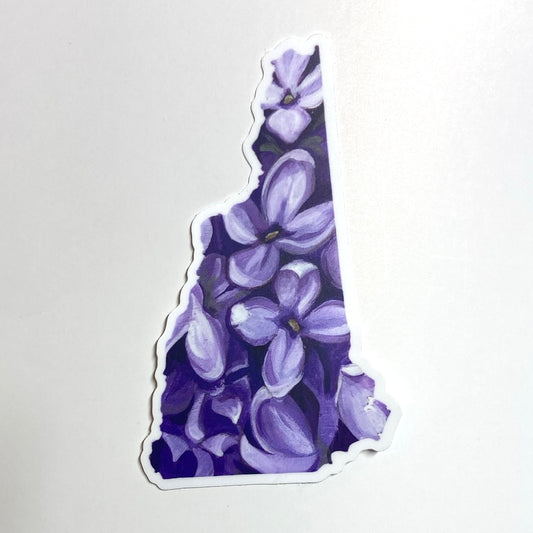 A sticker in the shape of New Hampshire with a painting of purple lilac flowers.