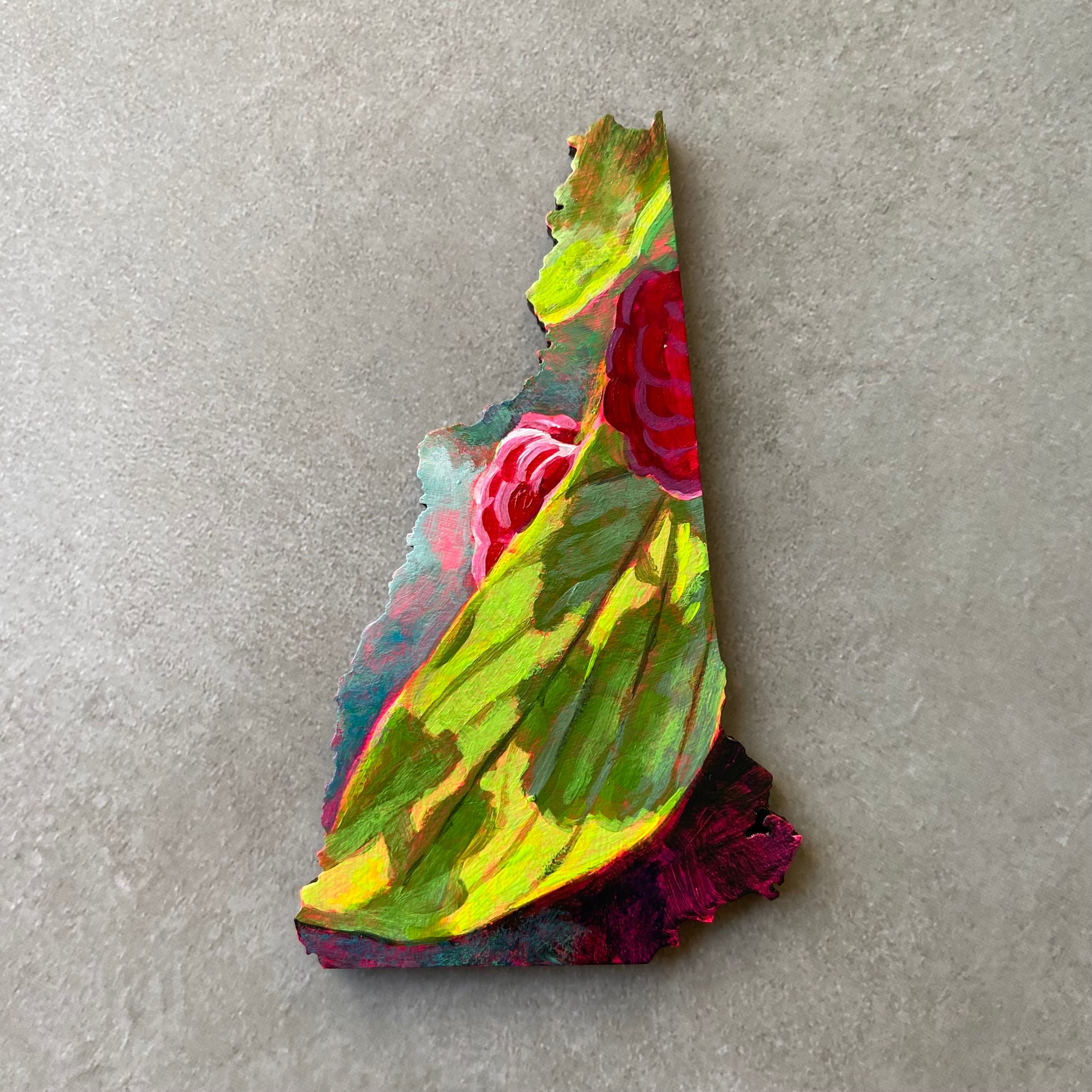 A New Hampshire-shaped painting showing a sunlit green leaf with part of two ripe raspberries visible. 