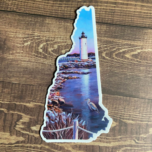 A vinyl sticker depicting a painted lighthouse scene with a heron, in the shape of New Hampshire. The sticker is mainly blue. 