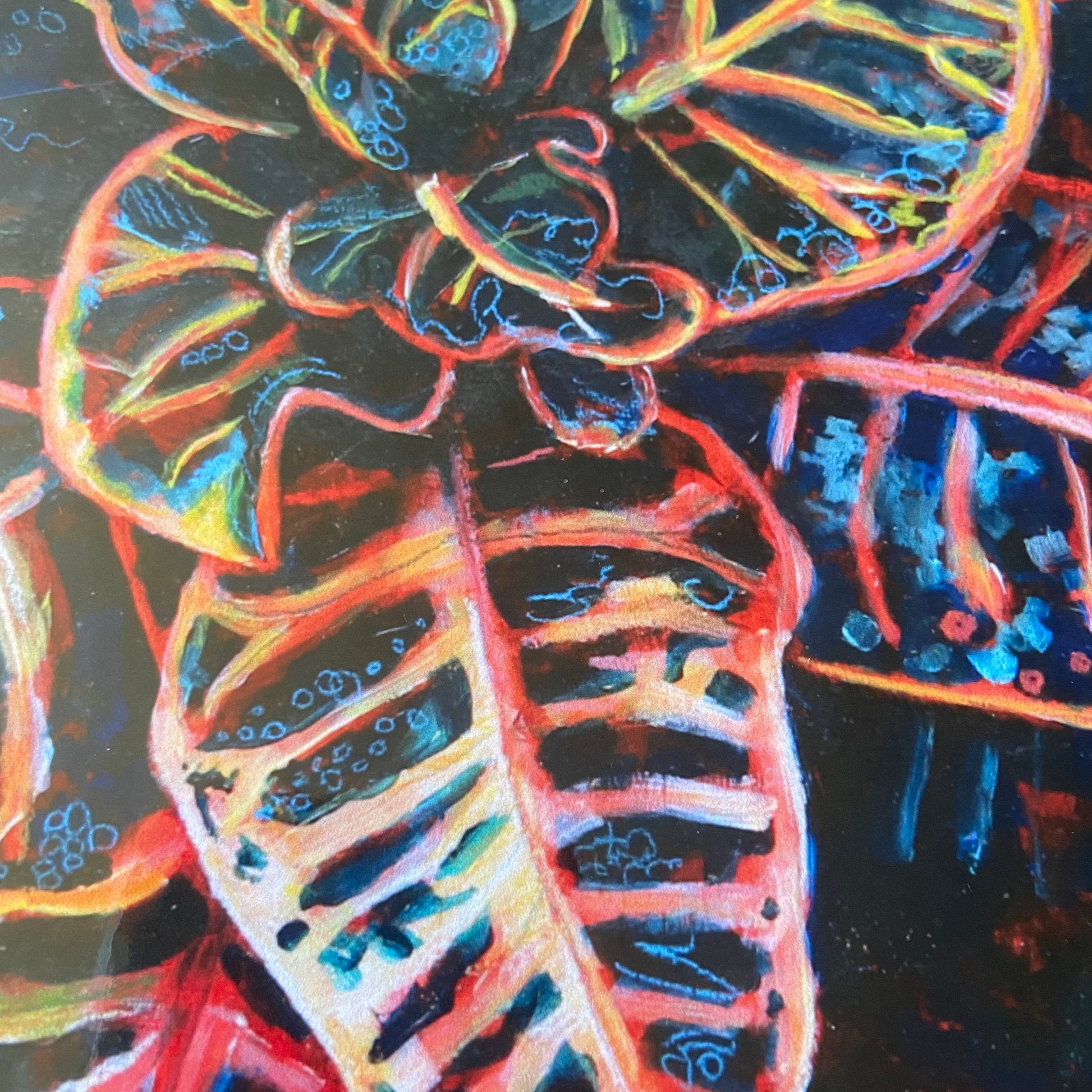 A close-up look at the center of the plant in the artwork. Pink, red and yellow colors show the light patches of the spotty plant, with vibrant blue highlights drawn in a whimsical way. The houseplant is mostly painted in primary colors.