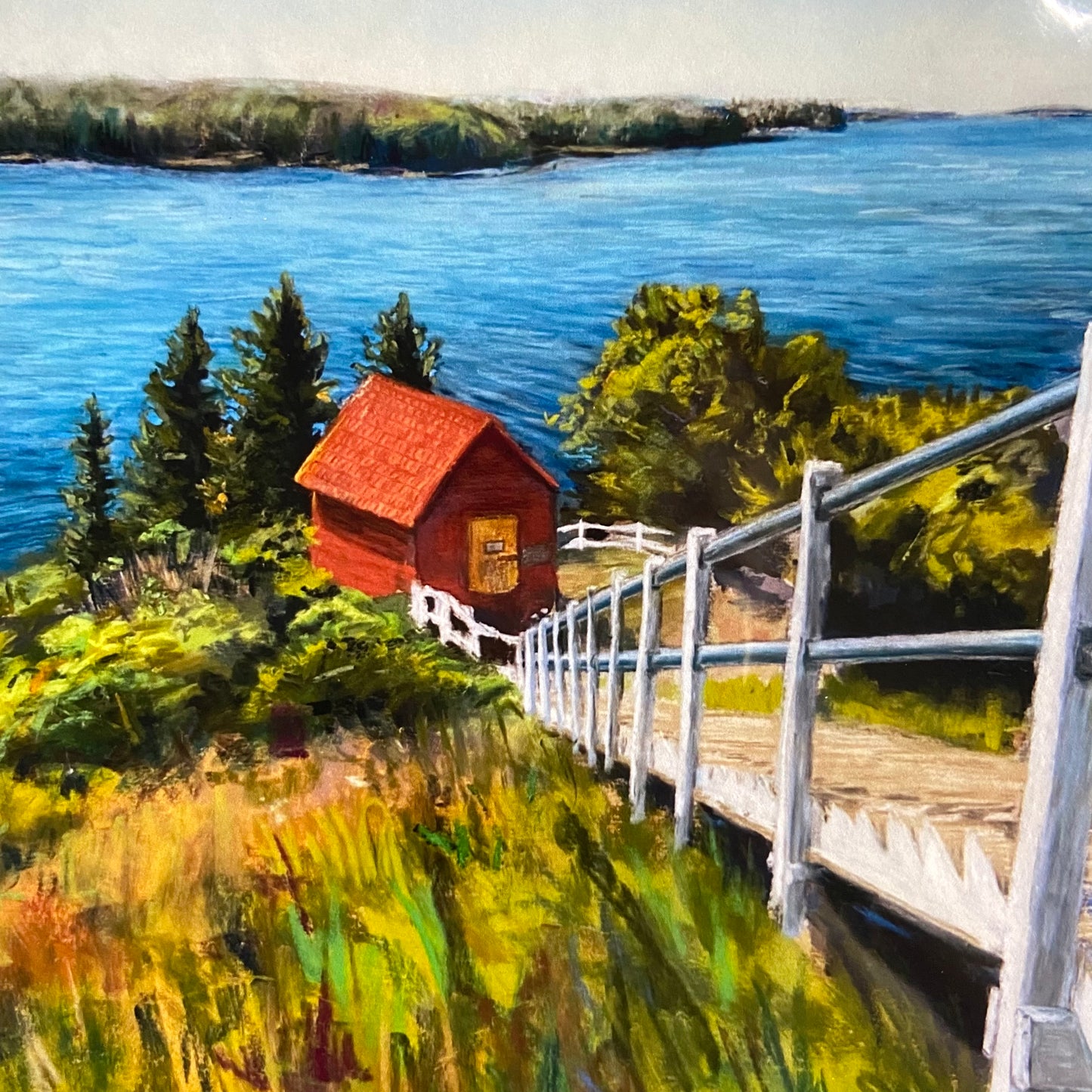 A close-up look at the print. The red utilities shed for the out-of-sight lighthouse had textured details like shingles and weathering. The vibrant colors of the greenery are slightly abstract and very joyful. This scene shows the serene Maine coast. 