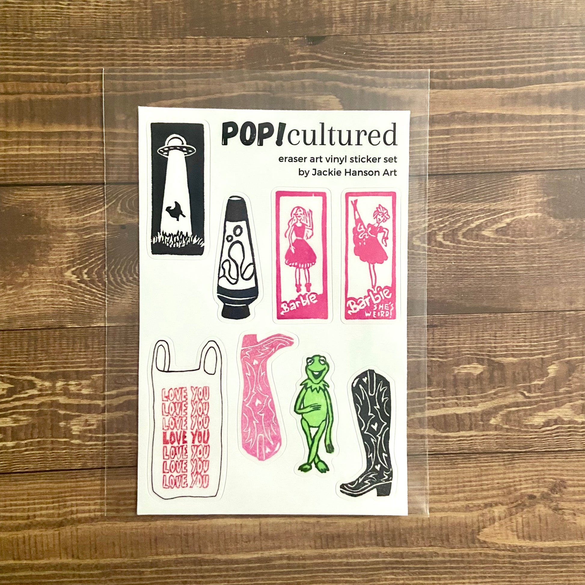 A 4x6 inch mainly white sticker sheet titled "POP! cultured". This set contains eight vinyl stickers of pop-culture-related relief prints made from erasers carved into stamps. It is wrapped in a protective plastic sleeve.