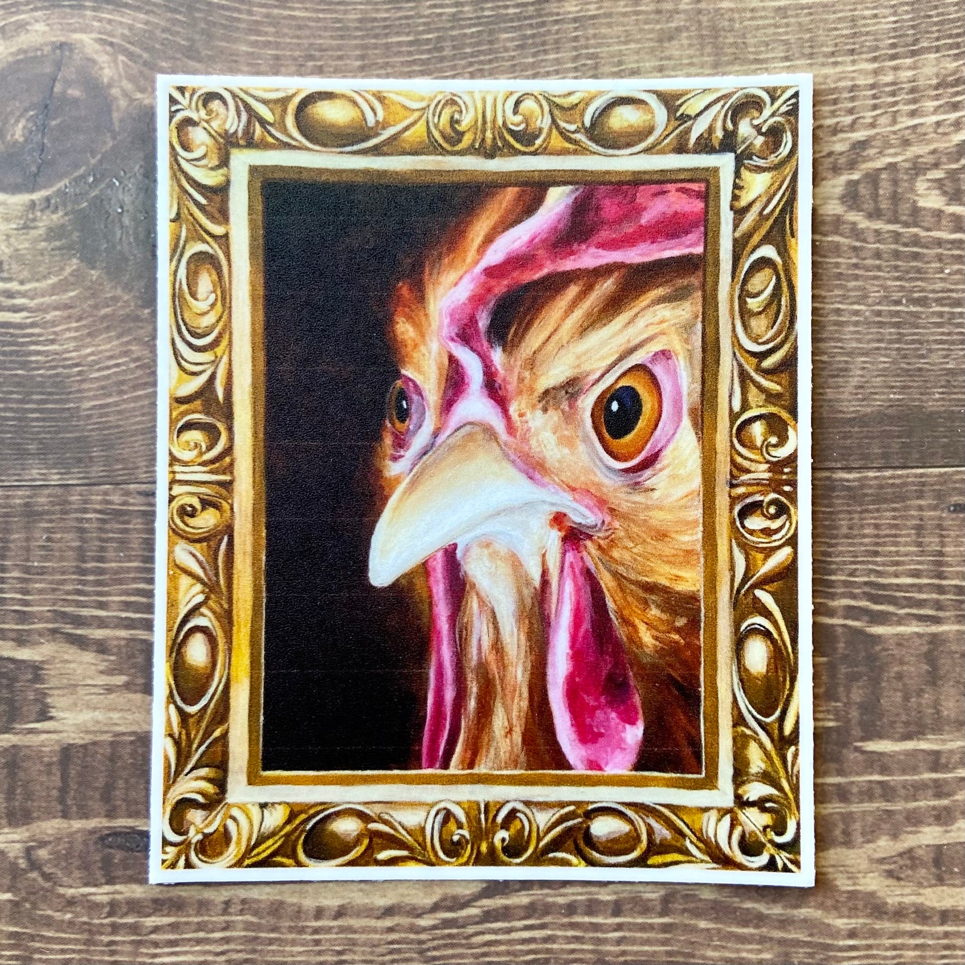 A sticker of my painting, "Regal Chicken" or "Hennifer", depicting a hen's angry face inside an ornate gold frame (also painted.) 