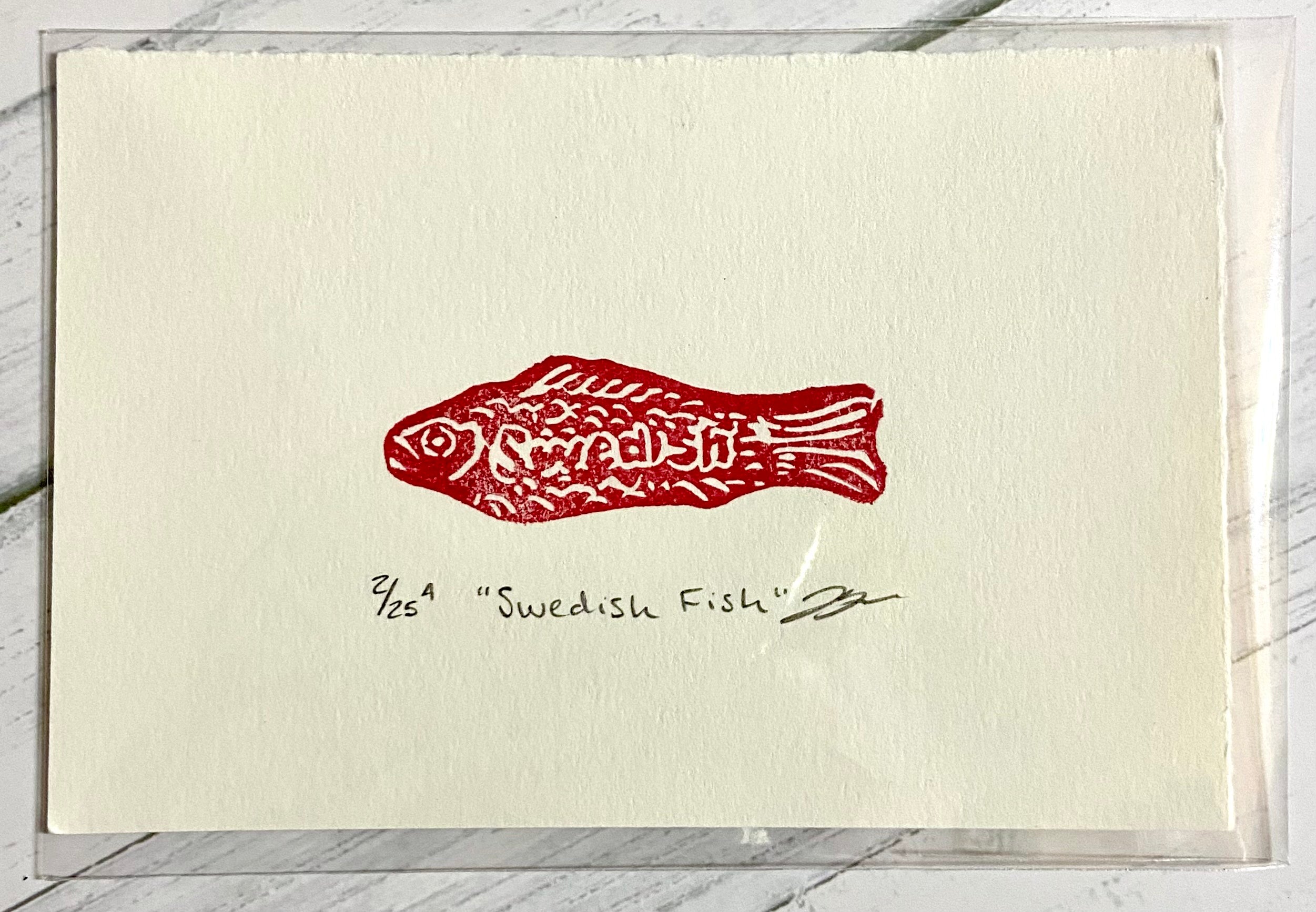 A red relief print of a Swedish Fish candy. The print is made by hand from an eraser and is numbered, titled, and signed.