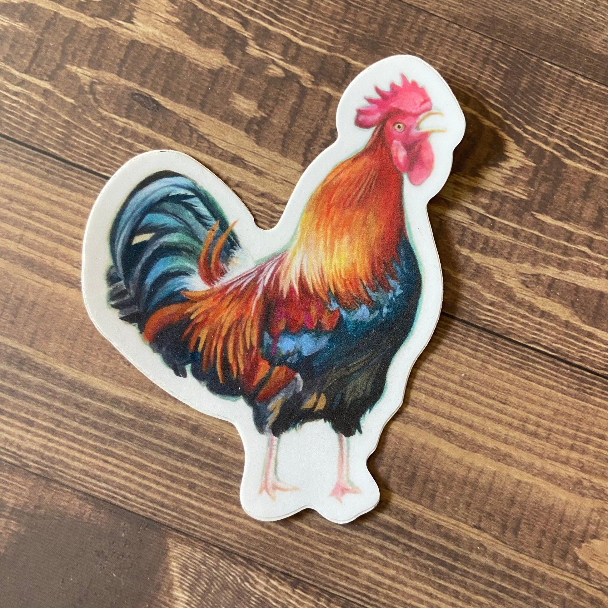 A die-cut sticker of a colorfully painted rooster crowing in a funny way.