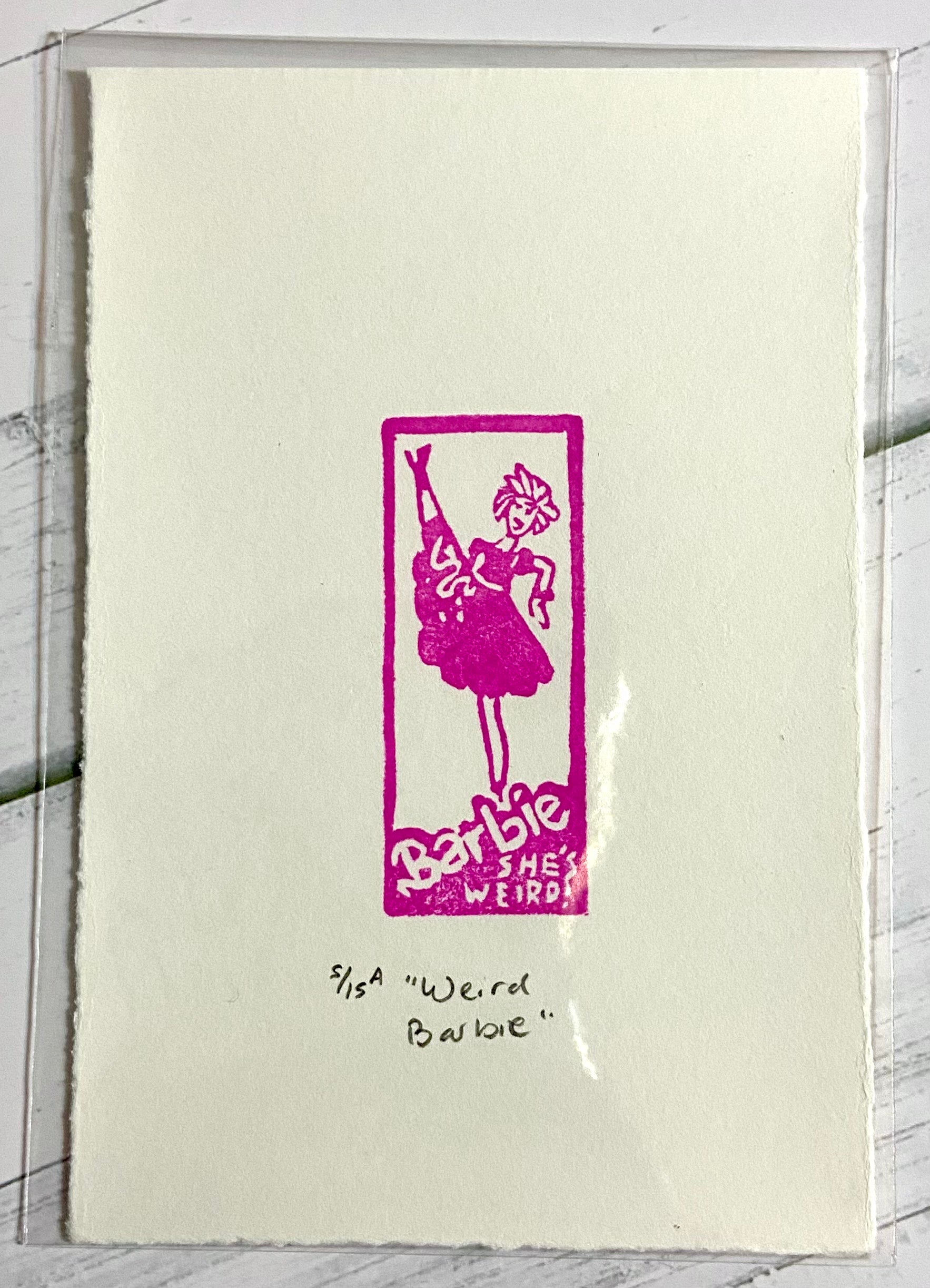 A pink relief print depicting Weird Barbie from the 2023 Barbie movie. the print is made by hand using a carved eraser, and is numbered, titled and signed. 