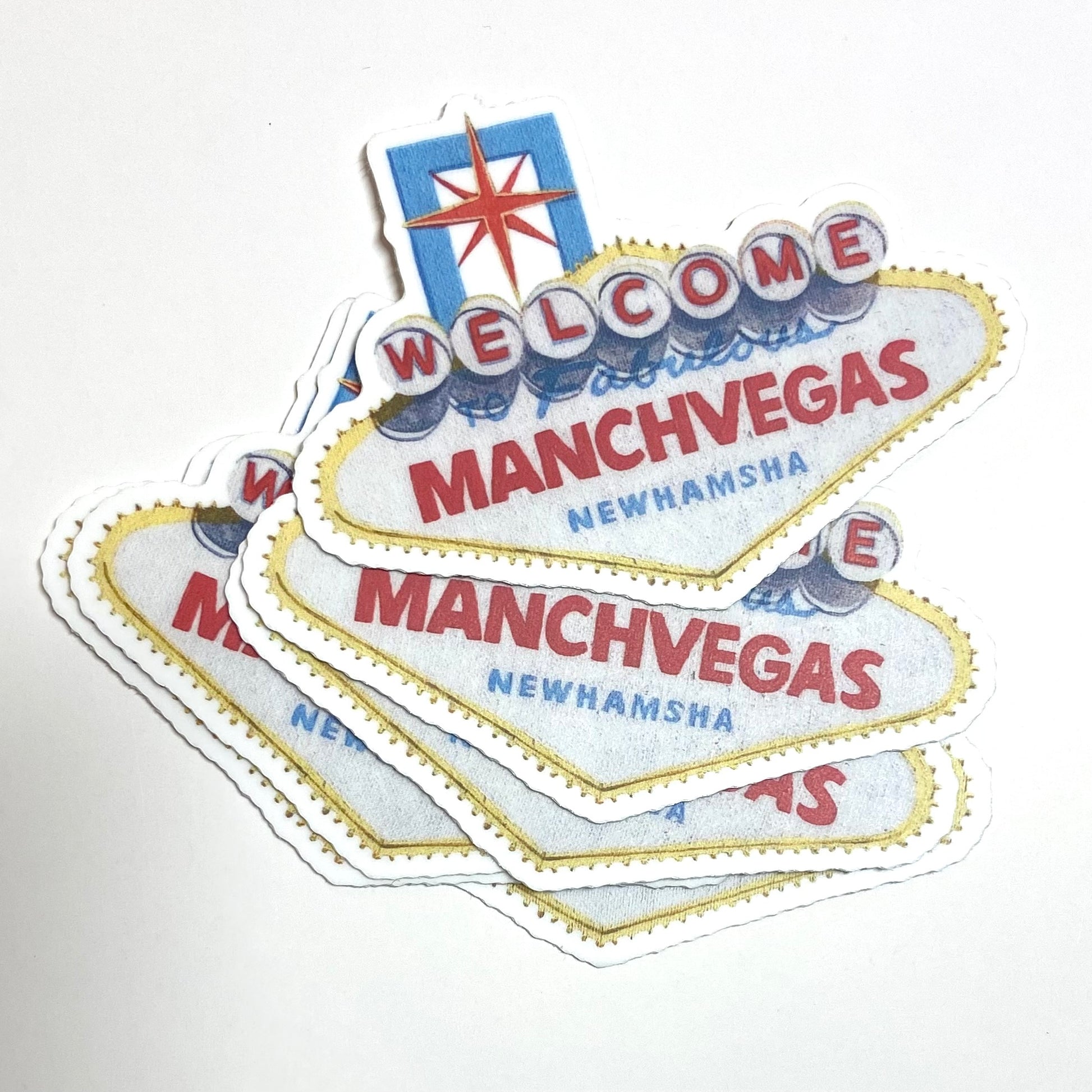 A pile of stickers showing the Las Vegas sign repainted to read "Welcome to Fabulous ManchVegas New Hamsha".