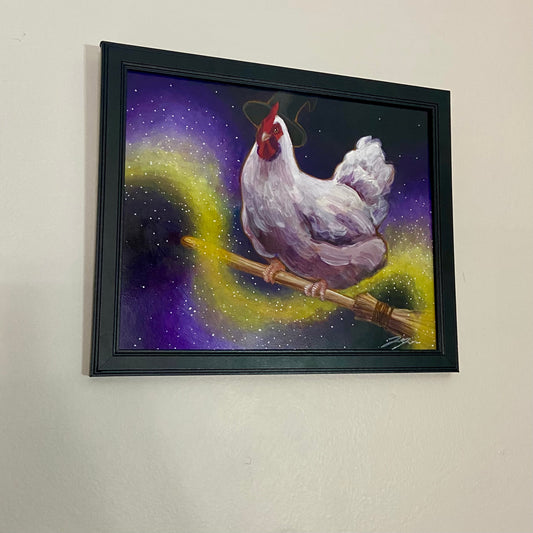 A painting of a chicken in a witch hat riding a broom across a dark sky. Yellow magic swirls through the air around her. The painting is in a black frame on a light gray wall.