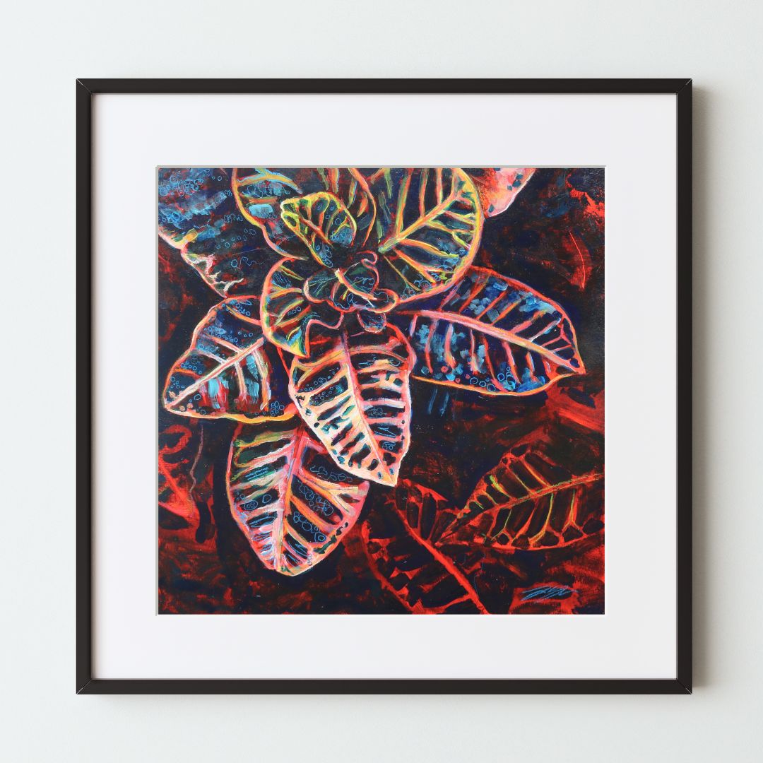 A mockup of a square botanical art print in a black frame with a white mat. The artwork is a top-down view of a Croton houseplant, mainly painted in bright red, black, and pastel colored highlights. This is bold, colorful wall decor for plant lovers.