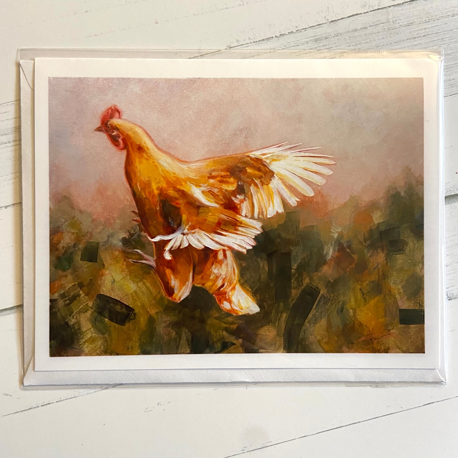 A landscape-style folded white greeting card depicting an orange hen in flight over an abstracted landscape background. 