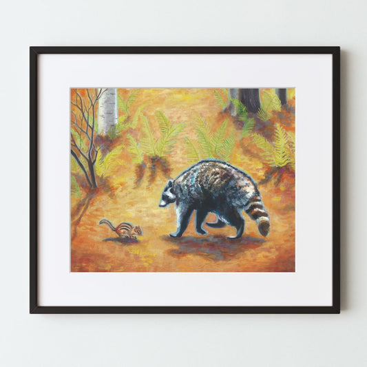 A mockup of an orange art print in a black frame with white mat. The print shows a realistically painted raccoon and chipmunk approaching one another as friends. They are in a forest with an orange floor, ferns in the background, and few trees.