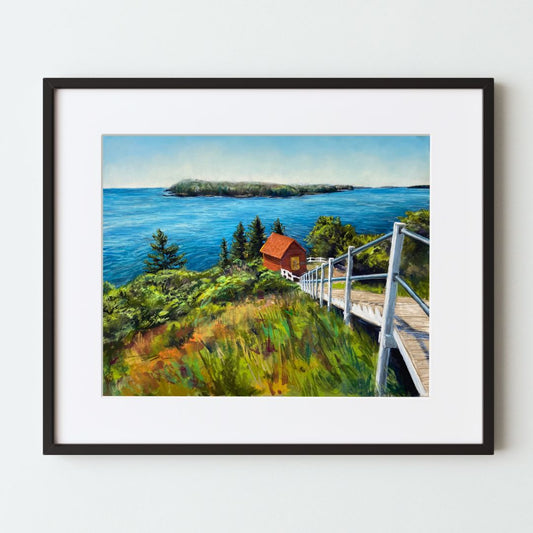 A mockup of a landscape art print in a black frame with a white mat. The painting looks down from the top of a hill, along a staircase down to a red shed, with trees, the ocean, and a distant island in the background.